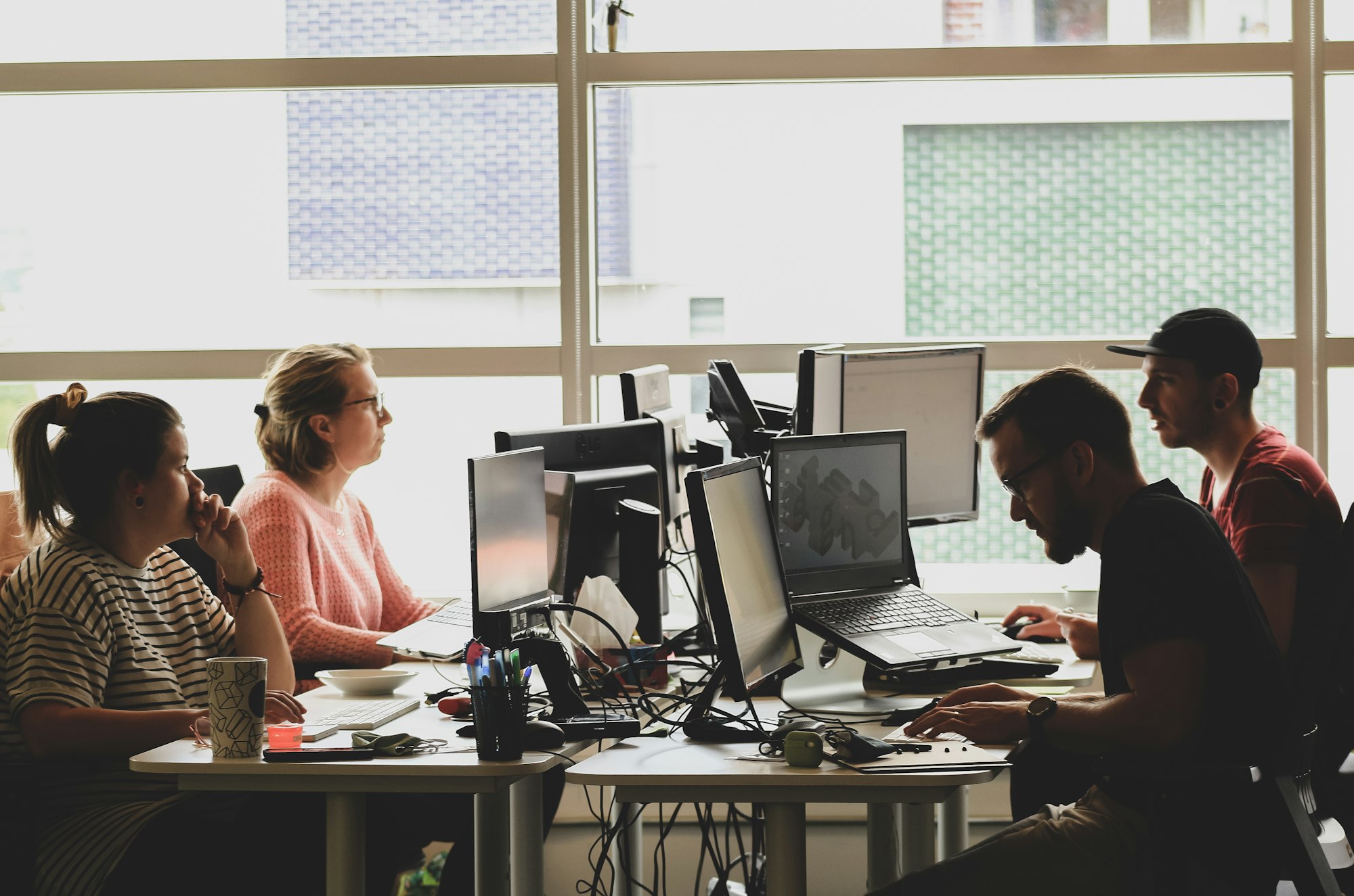 A focused worker at a desk with a laptop, natural daylight.