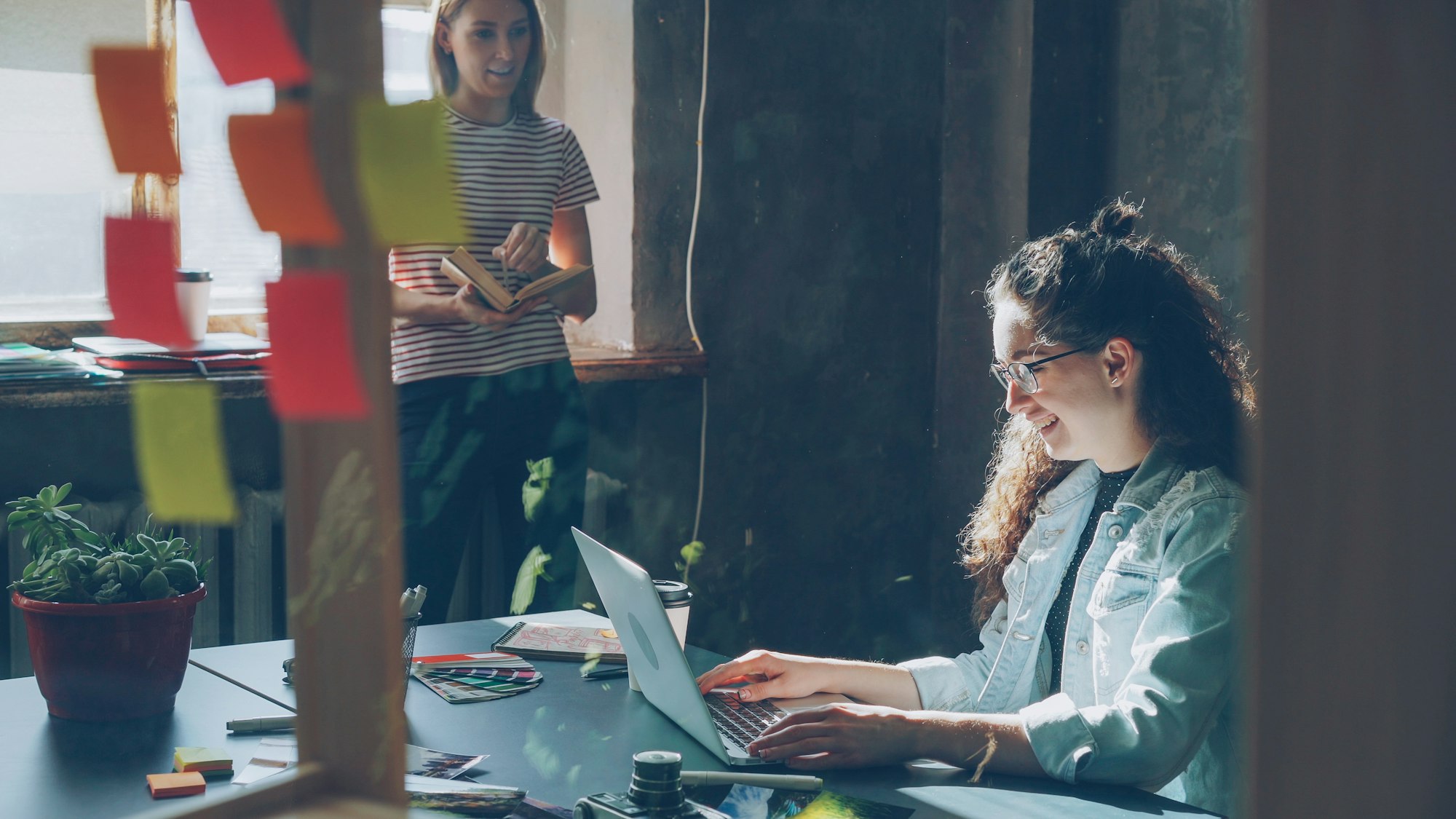 Two colleagues working together in a bright open-plan office.